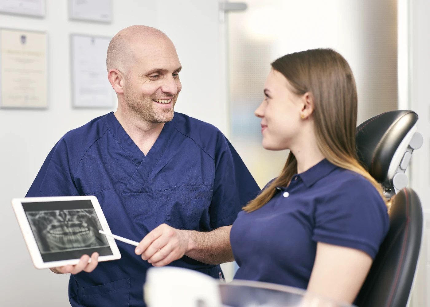 Zahnarzt zeigt Patientin Röntgenbild auf Tablet in der Praxis Dr. Schmutz.
