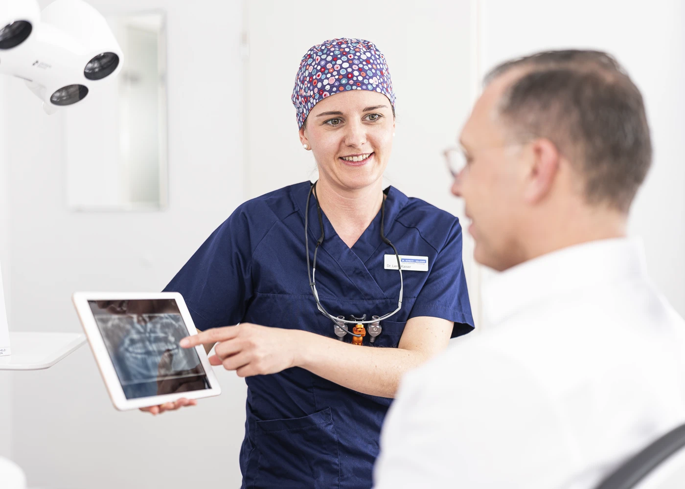 Zahnärztin erklärt Röntgenaufnahme einem Patienten in der Praxis Dr. Schmutz.