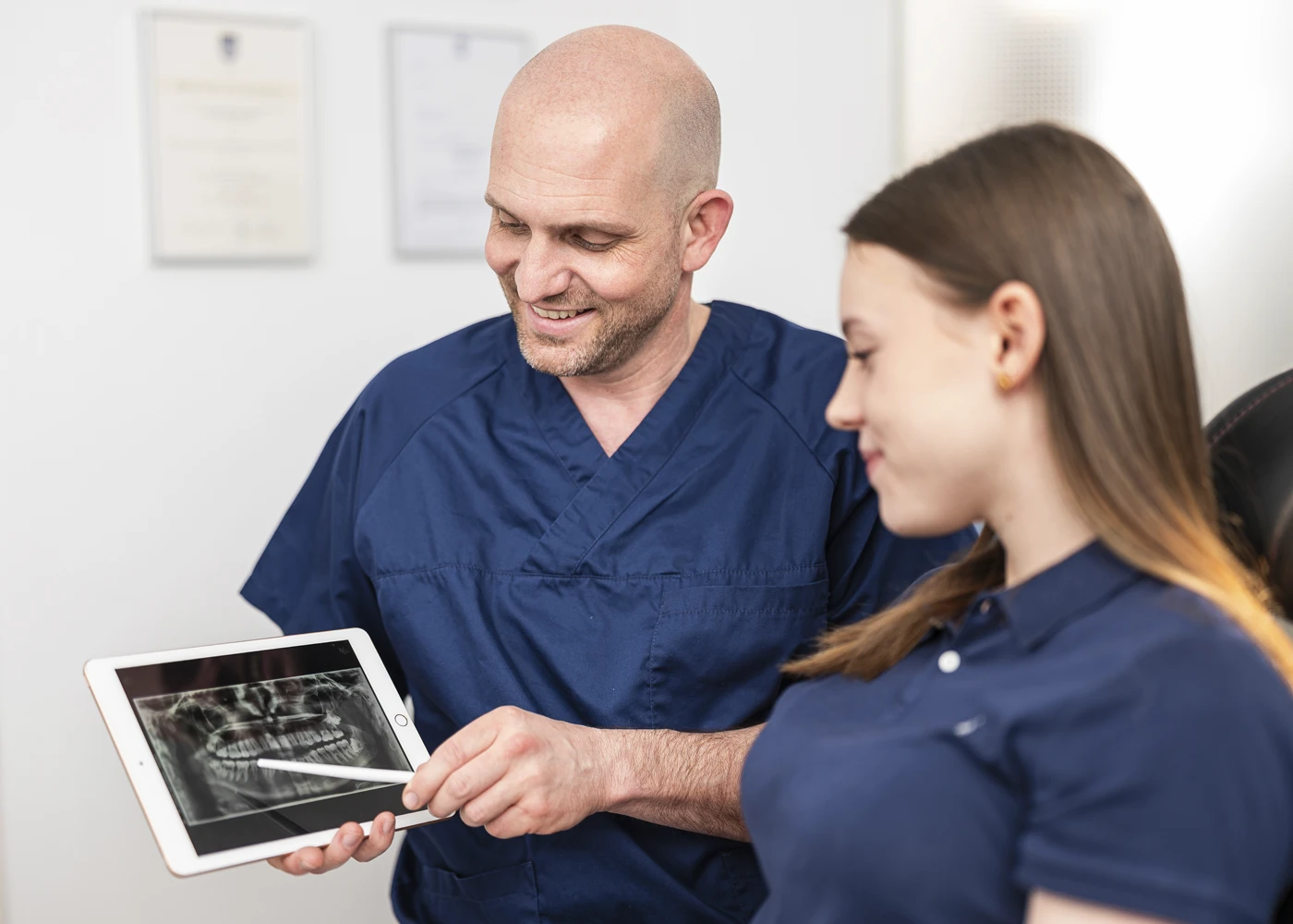 Zahnarzt zeigt Patientin Röntgenbild auf Tablet in der Praxis Dr. Schmutz.